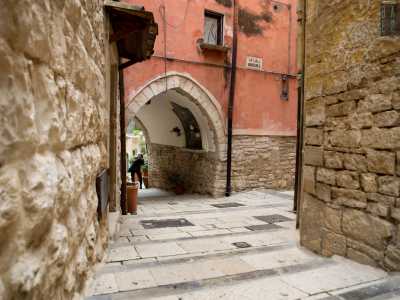 Svoltiamo ora a destra, in via Ruggiero, per raggiungere un bianchissimo arco di forma ogivale che ospita l�edicola della Vergine Immacolata, omaggiata da due fioriere colme di rose rosse